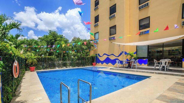 A swimming pool with a lifebuoy, surrounded by a fence, and a building with a wave mural in the background.
