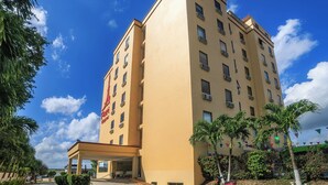 A multi-story hotel with a flat facade, a covered entrance, and a clear sky.