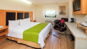 A hotel room with a bed, a desk, a chair, a television, and a window with a view.