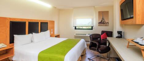 Habitació d'hotel amb llit, escriptori, cadira, televisió i finestra amb vistes.