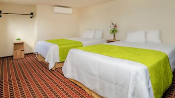 Habitación de hotel con dos camas, una mesita de noche pequeña, aire acondicionado de pared y alfombra estampada.