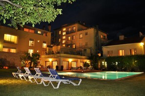 A poolside area with lounge chairs and a swimming pool, surrounded by buildings with multiple windows and balconies. - Aparthotel Solé (La Pobla de Segur)