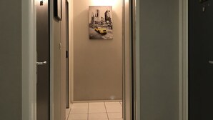 A hallway with a tiled floor, a framed picture on the wall, and a door on the right. - Résidence Carpe Diem (Marseille)