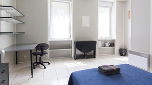 A room with a bed, a desk, a chair, and a radiator. - Résidence Carpe Diem (Marseille)