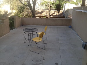 A patio with a round metal table and four chairs, surrounded by a low wall and trees. - Résidence Carpe Diem (Marseille)