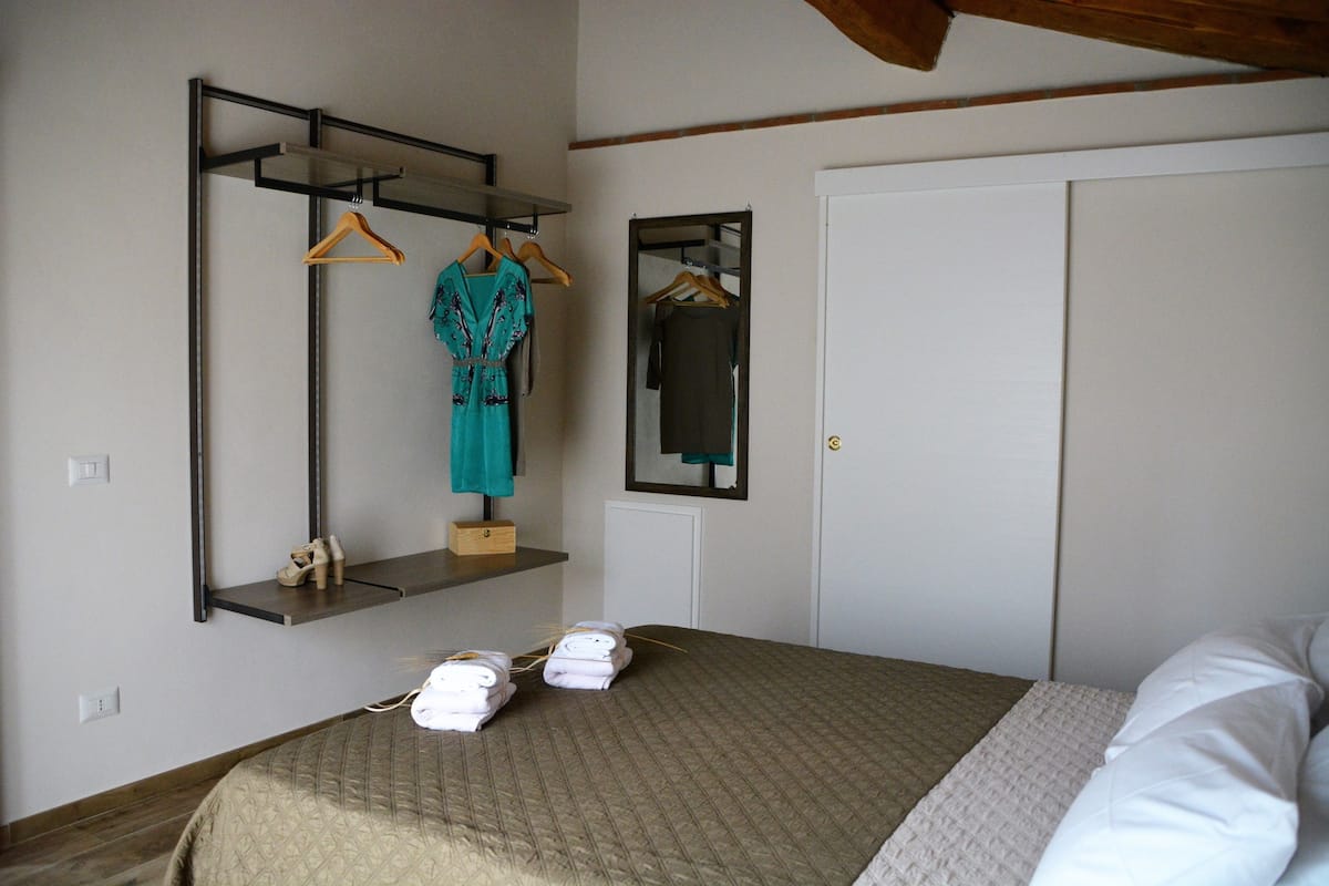 Une chambre à coucher avec un lit, un portant à vêtements, un miroir et une porte.