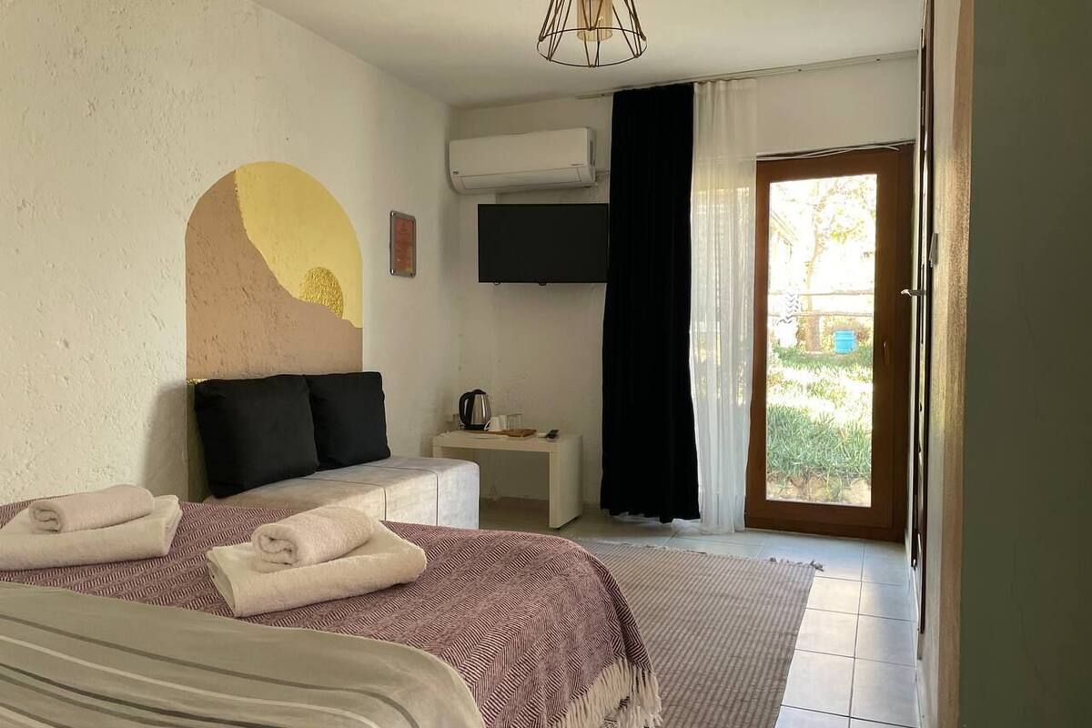 A bedroom with a bed, bedside table, and a TV mounted on the wall.