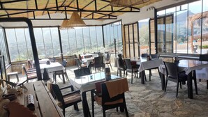 Un restaurant amb sòl de pedra, grans finestres i vistes al paisatge.