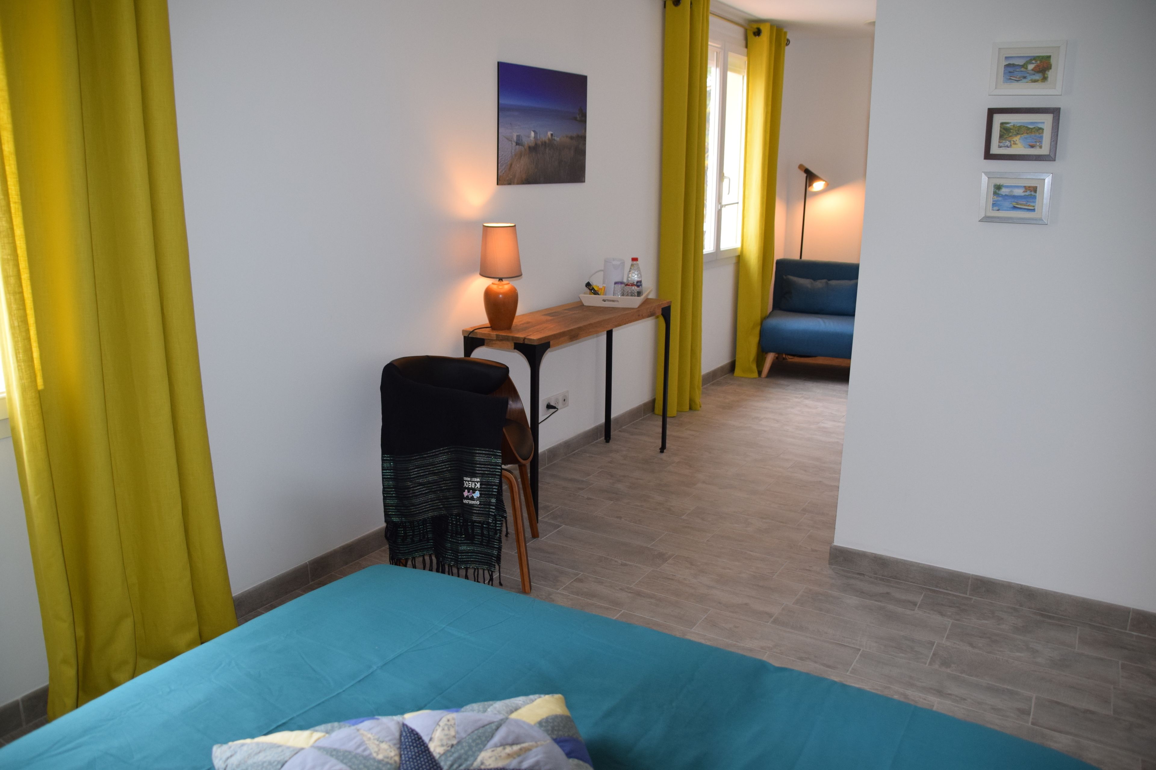 Una habitación con cama, un escritorio con lámpara, una silla y una mesa con bandeja.