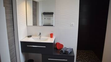 Un baño moderno con un lavamanos blanco, tocador negro y un objeto con forma de corazón rojo sobre la encimera.