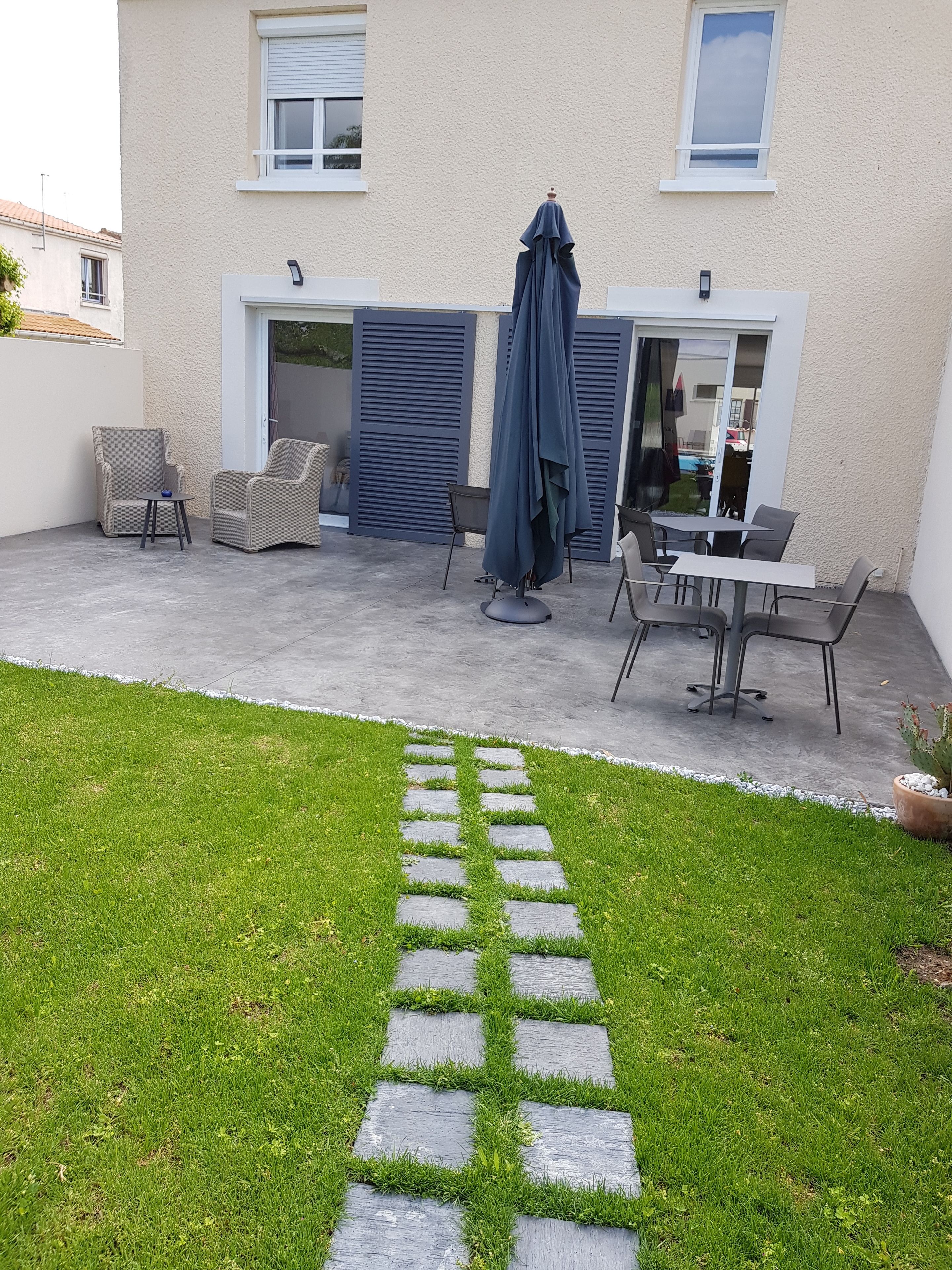 Un'area patio con mobili da esterno, un vialetto in pietra e un edificio con un'entrata garage.