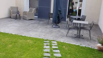 Un'area patio con mobili da esterno, un vialetto in pietra e un edificio con un'entrata garage.