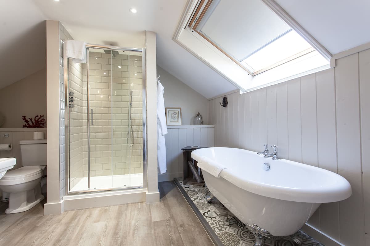 Een moderne badkamer met een douche met glazen wand, een vrijstaand bad en een dakraam.