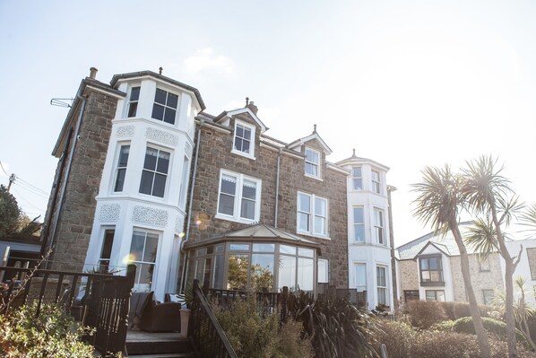 A large, multi-story stone building with a bay window and a conservatory.