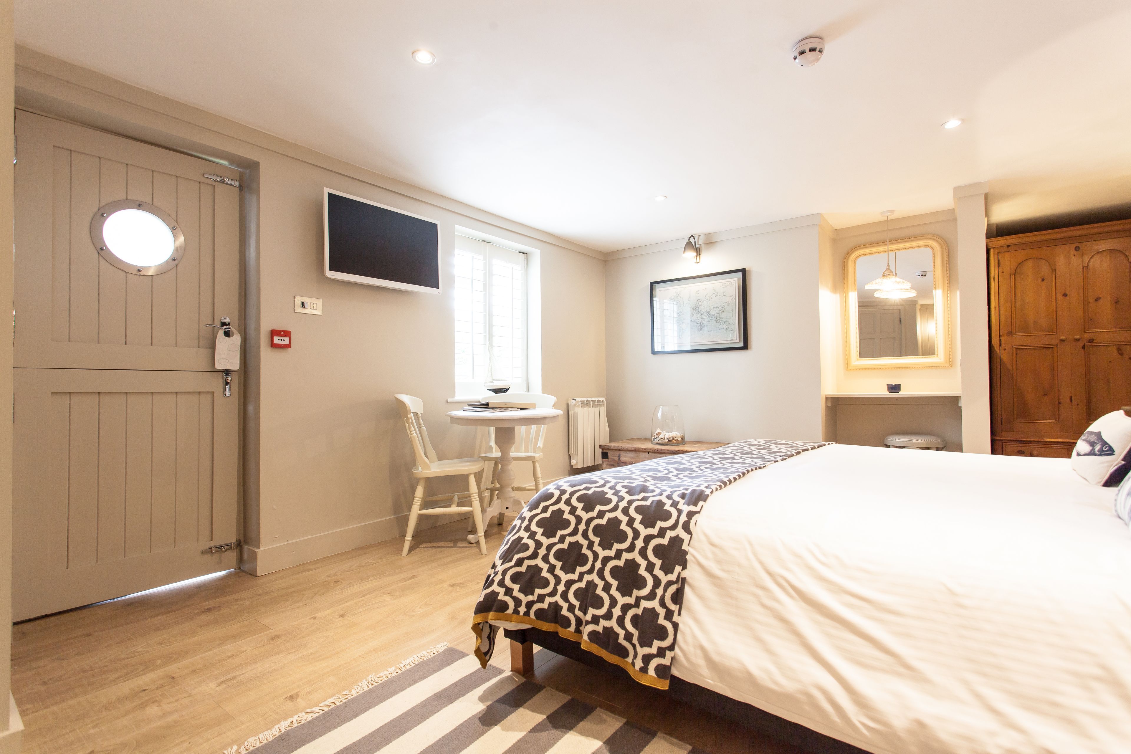 A bedroom with a bed, a desk, a chair, a television, and a wardrobe.