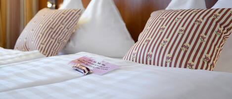 A hotel room with a bed, pillows, a lamp, and a note on the bed.
