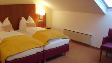 A hotel room with two beds, a nightstand, a lamp, a chair, and a skylight.