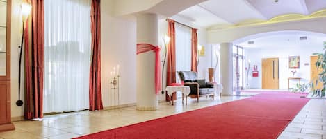 A hotel lobby with a red carpet, a leather chair, and a white table with a red cloth.
