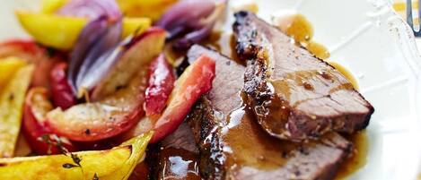 A plate of food with sliced meat and roasted vegetables.