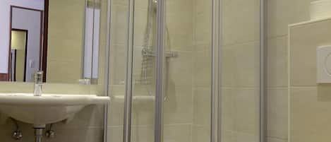 Un baño moderno con ducha de vidrio, lavabo e inodoro.
