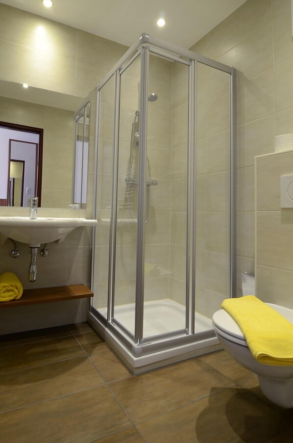 Un baño moderno con ducha de vidrio, lavabo e inodoro.