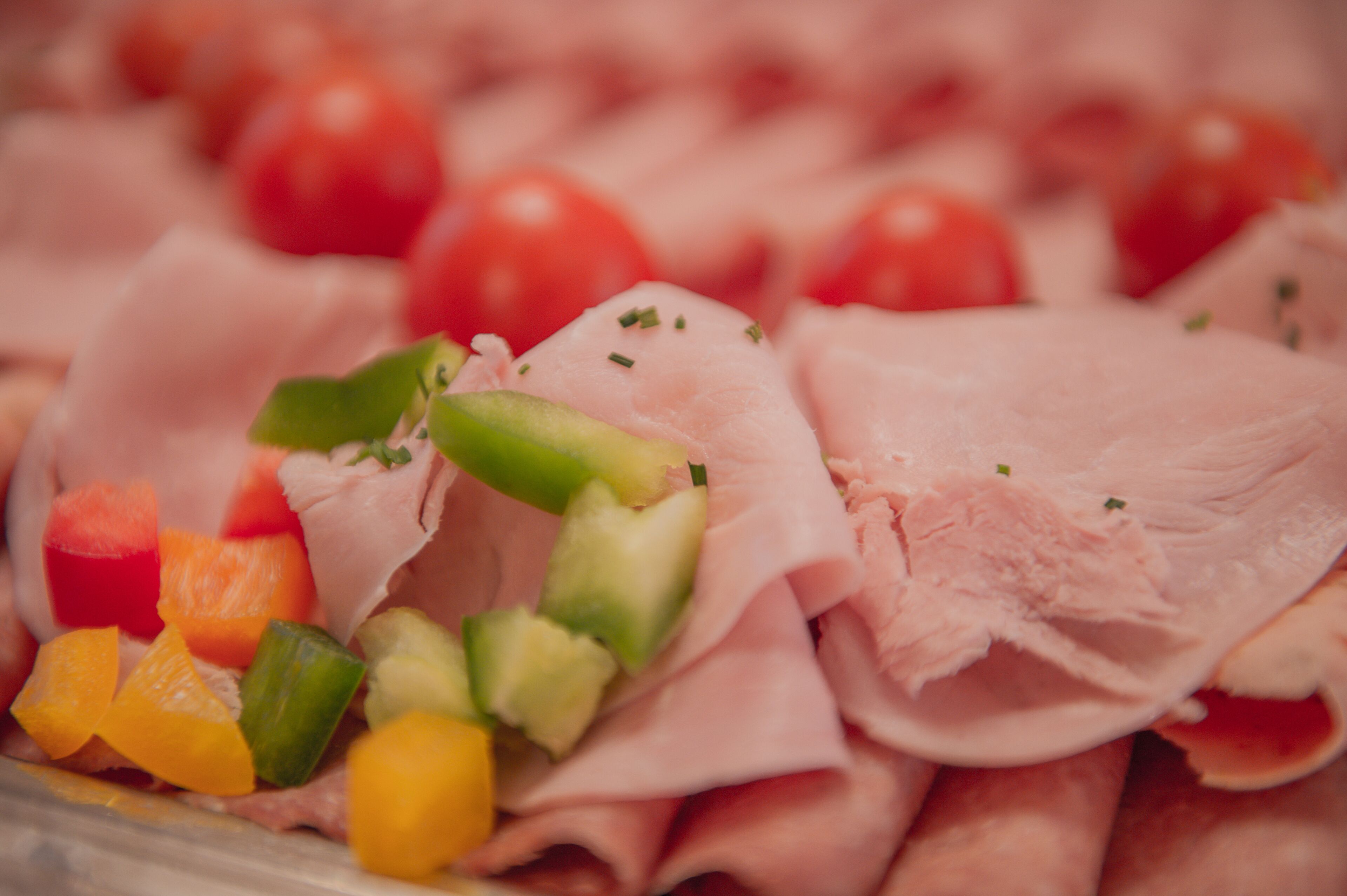 A close-up of a food platter with sliced meat, cherry tomatoes, and diced vegetables.