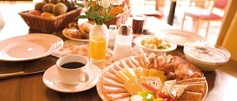 Desayuno con platos de comida, una taza de café y un bol de fruta.