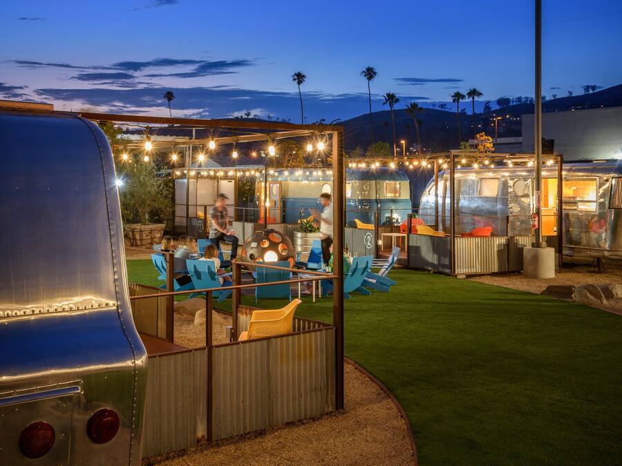 A well-lit outdoor area with a covered seating area, a grill, and a trailer kitchen.