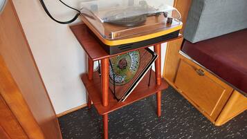 Una pequeña mesa de madera con un tocadiscos, un plato decorativo y un banco.