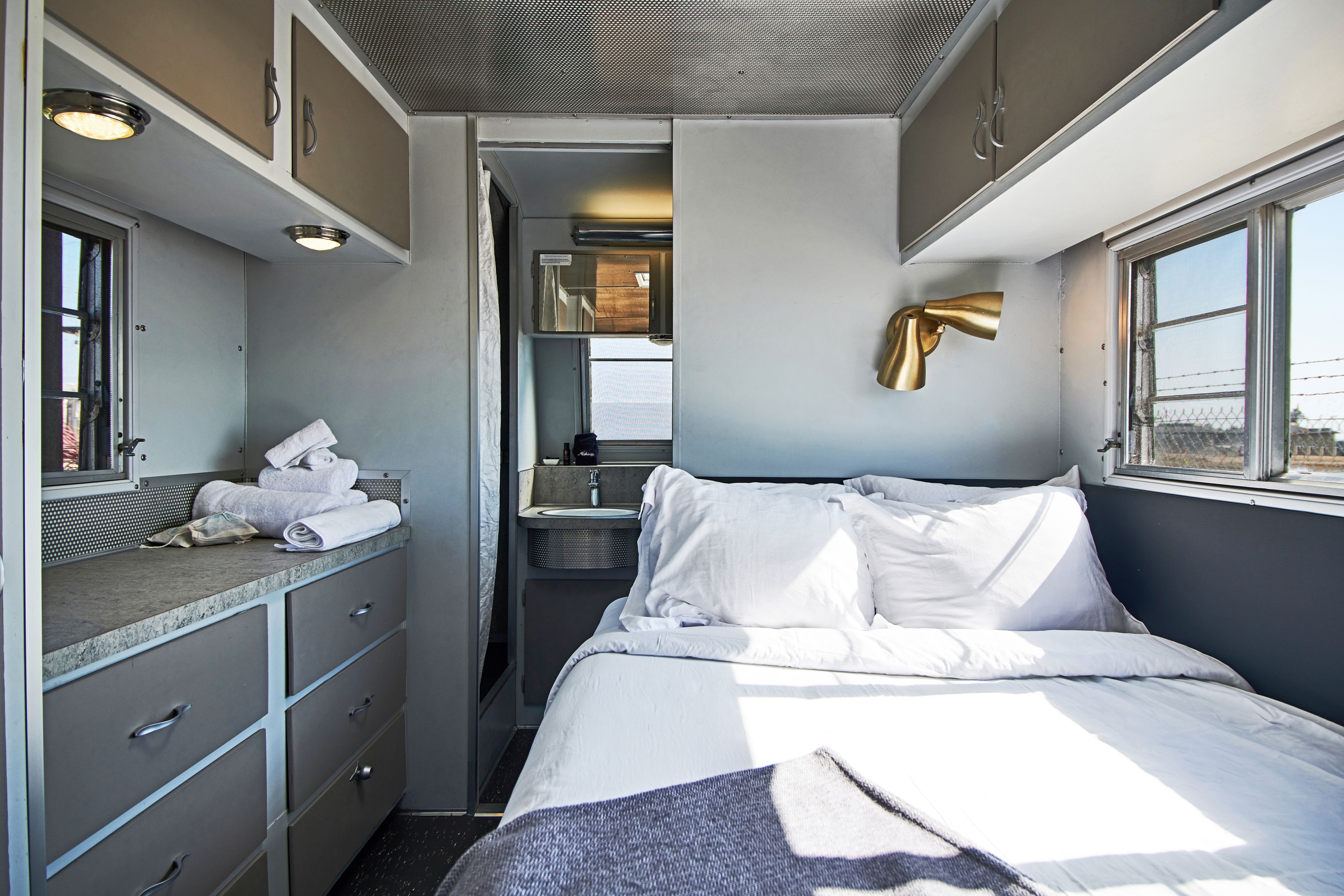 A compact, well-lit room with a bed, a small bathroom, and a window providing a view.