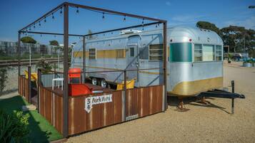 Una caravana vintage con un área cerrada pequeña que tiene una mesa y sillas, con la leyenda '3 Park Here 4'.