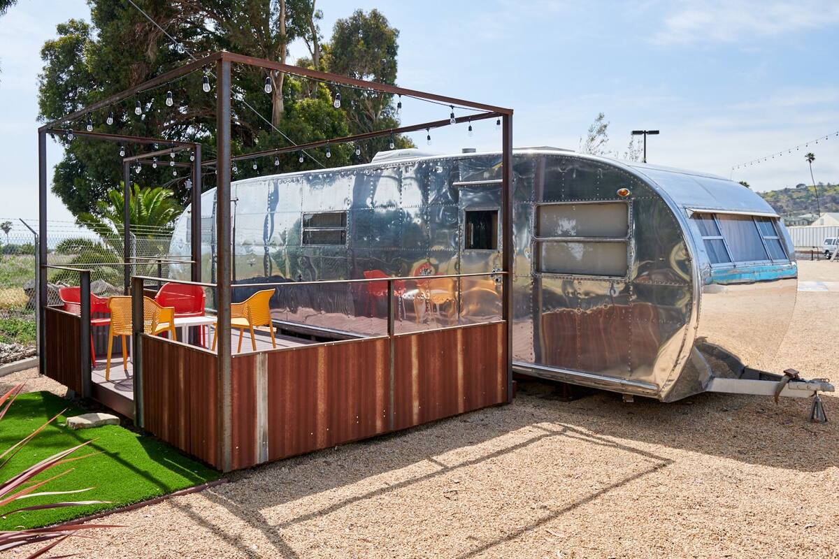 A mobile home with a small outdoor seating area, including a table and chairs.