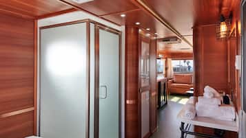 A modern interior with a bed, a wardrobe, a table with towels, and a seating area with a view.