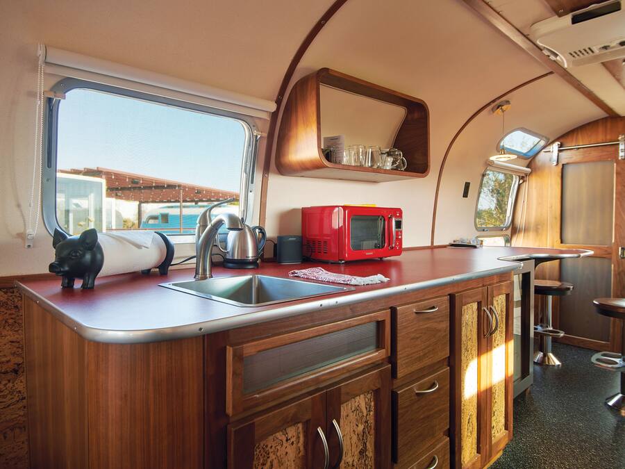 A compact kitchen with a sink, a red microwave, and a small window.