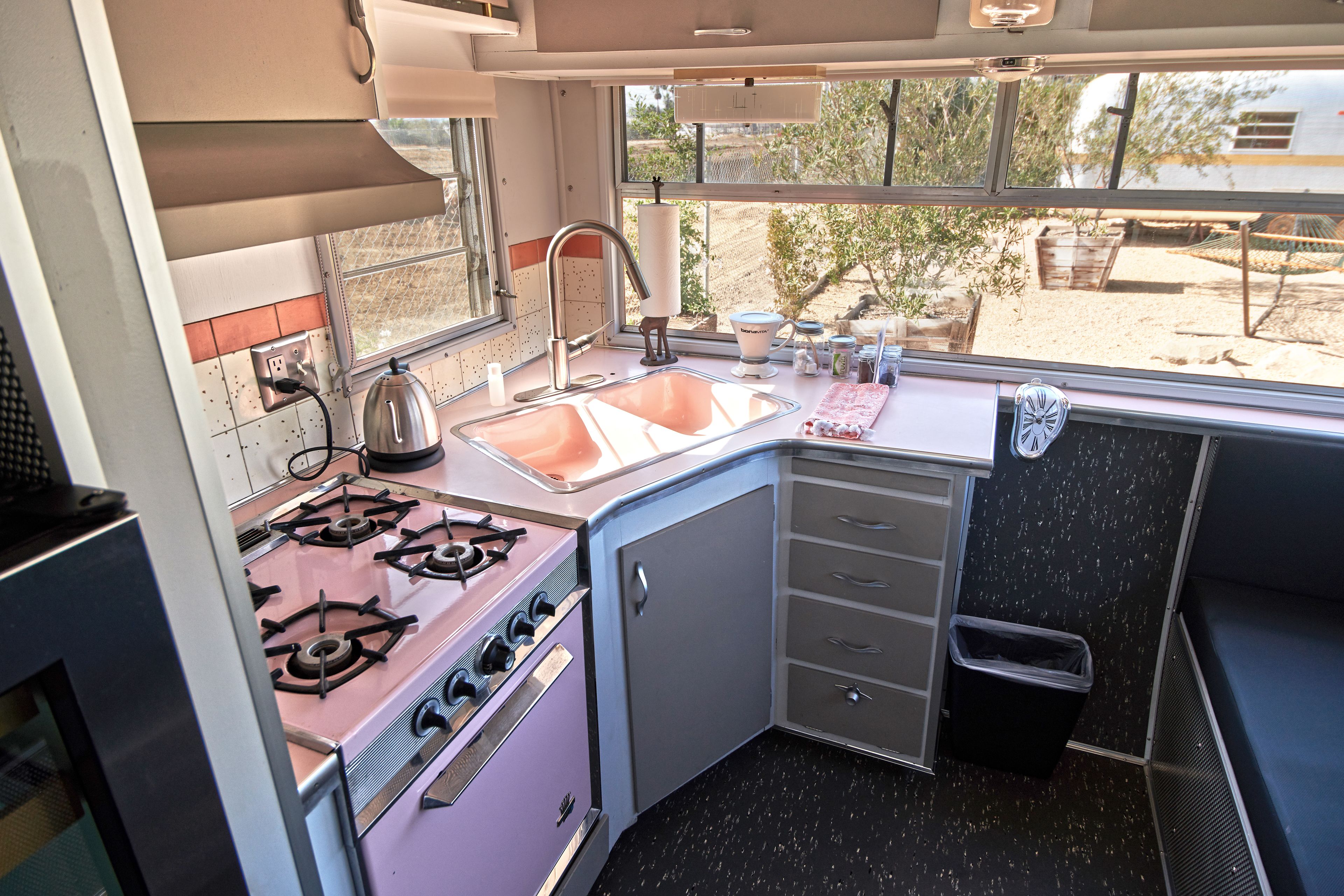 A compact kitchen with a gas stove, sink, and a window offering a view of the outdoors.