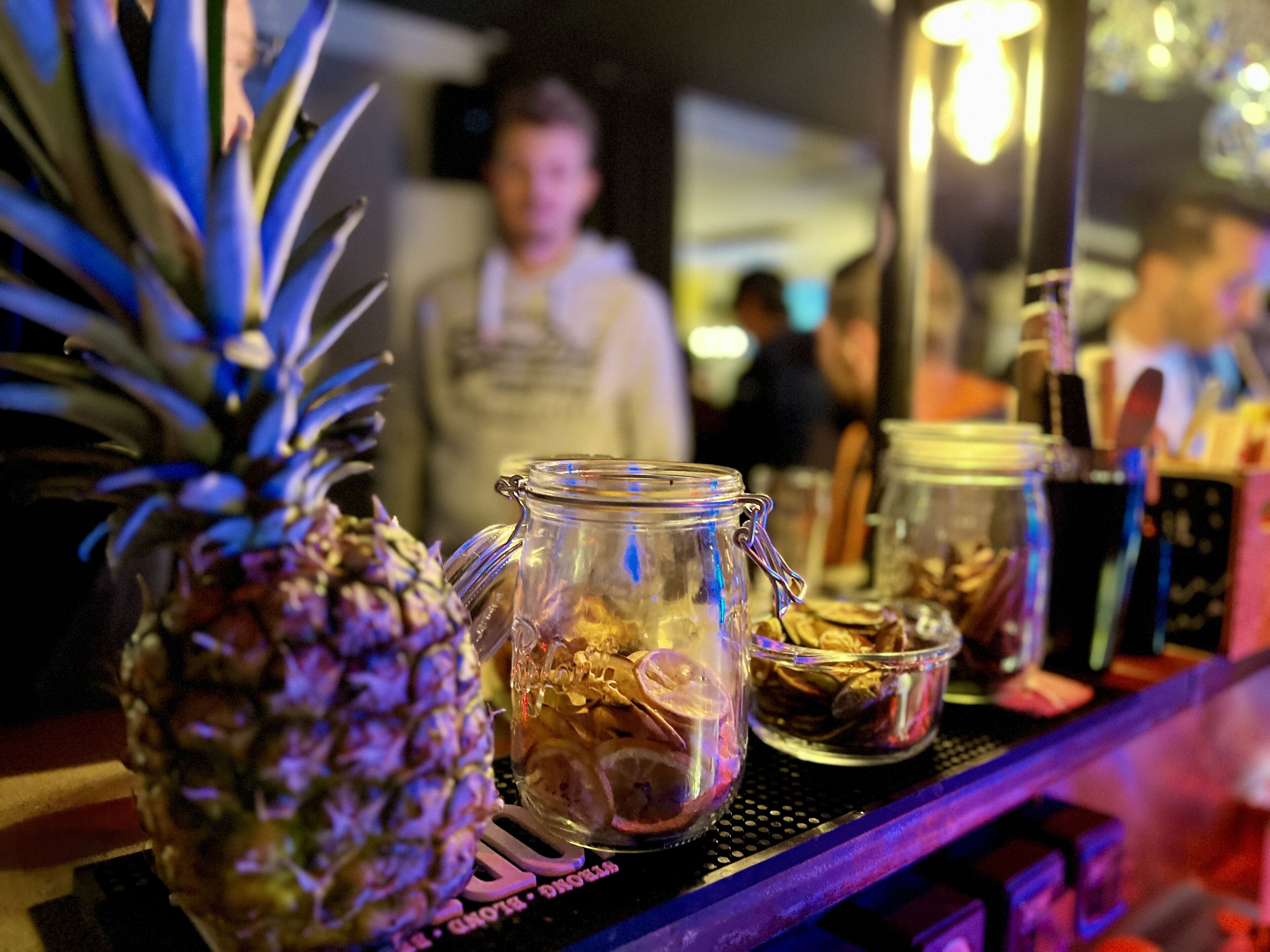 Una barra con una piña, un tarro de vidrio con cierre metálico y un cuenco pequeño de nueces.