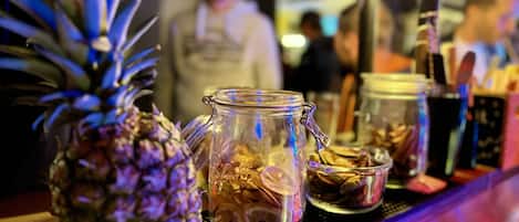 Una barra con una piña, un tarro de vidrio con cierre metálico y un cuenco pequeño de nueces.
