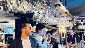Een bar met een toonbank, glazen en diverse barbenodigdheden.