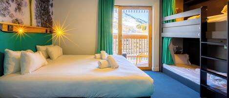 A hotel room with a large bed, a bunk bed, a balcony with a view of a snowy landscape, and a painting on the wall.