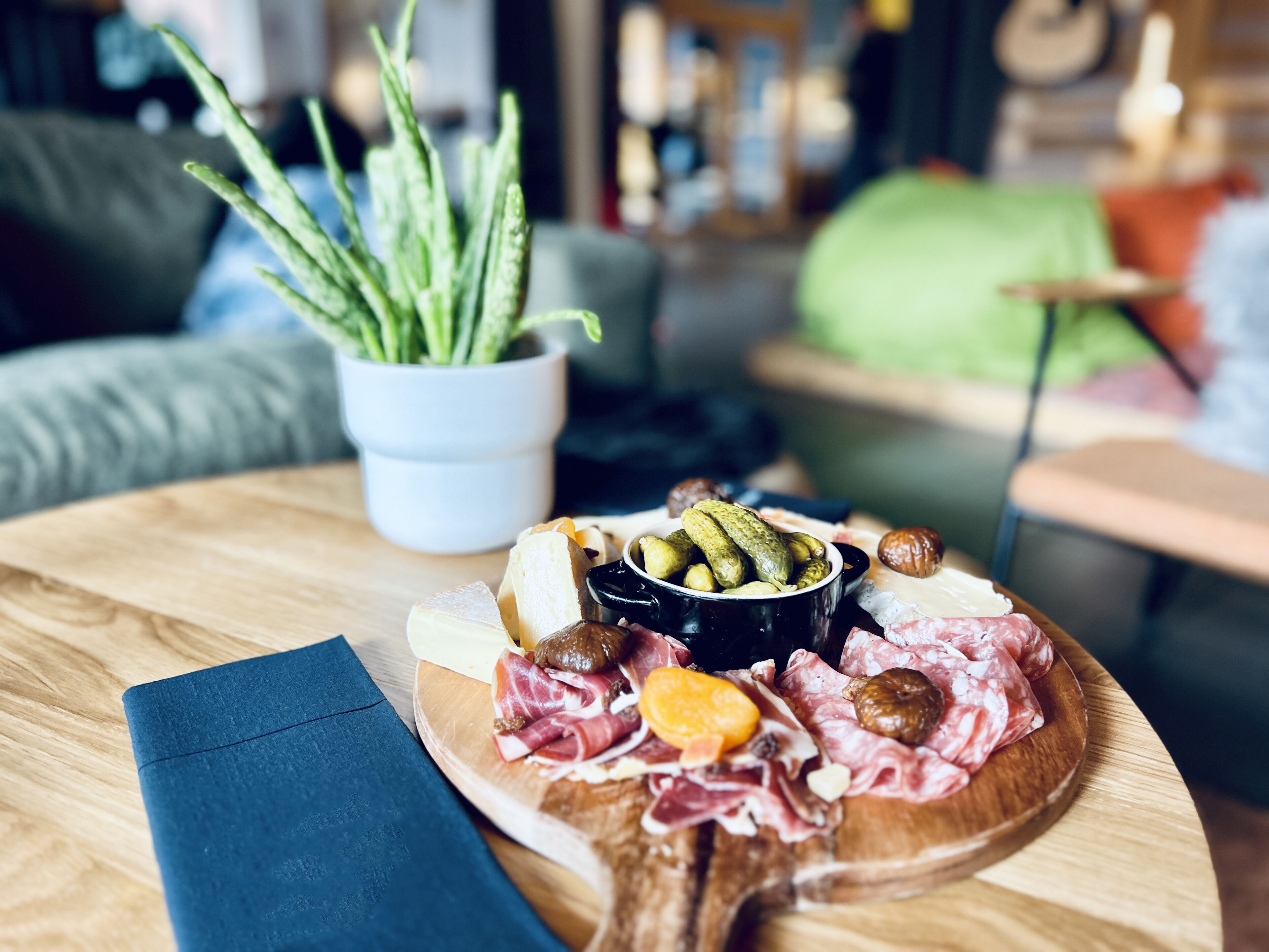 Une planche en bois garnie de différents fromages, de charcuteries et d’olives.