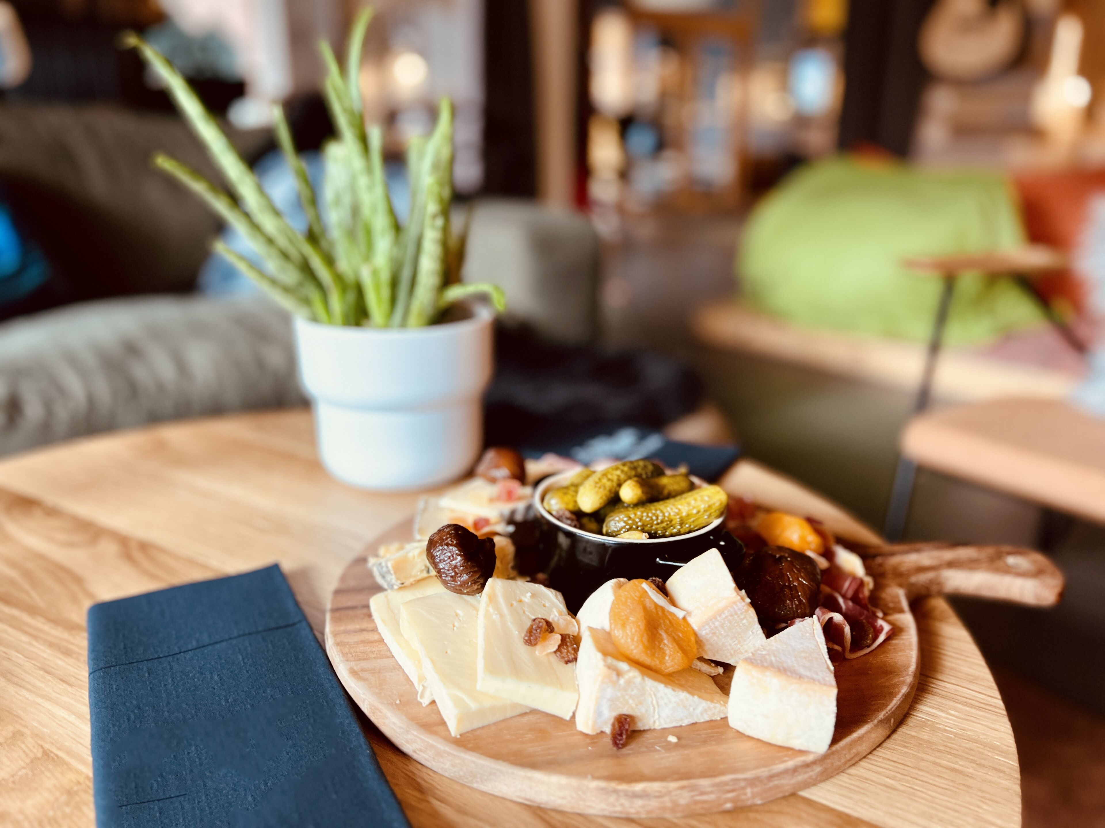 Ein Holztisch mit einer Käseplatte, Oliven und Essiggurken.