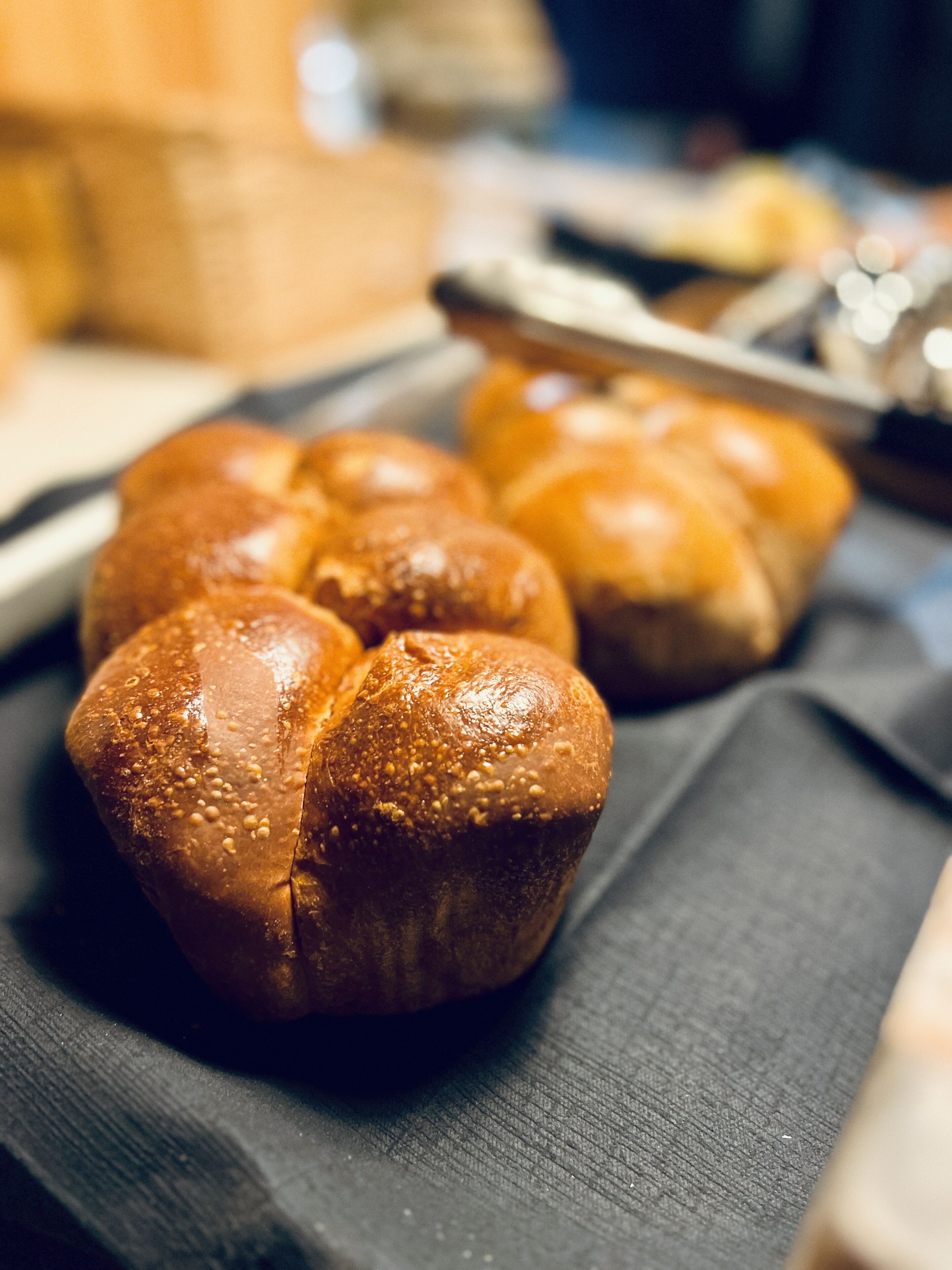 A close-up of a loaf of bread with sesame seeds on a dark cloth.