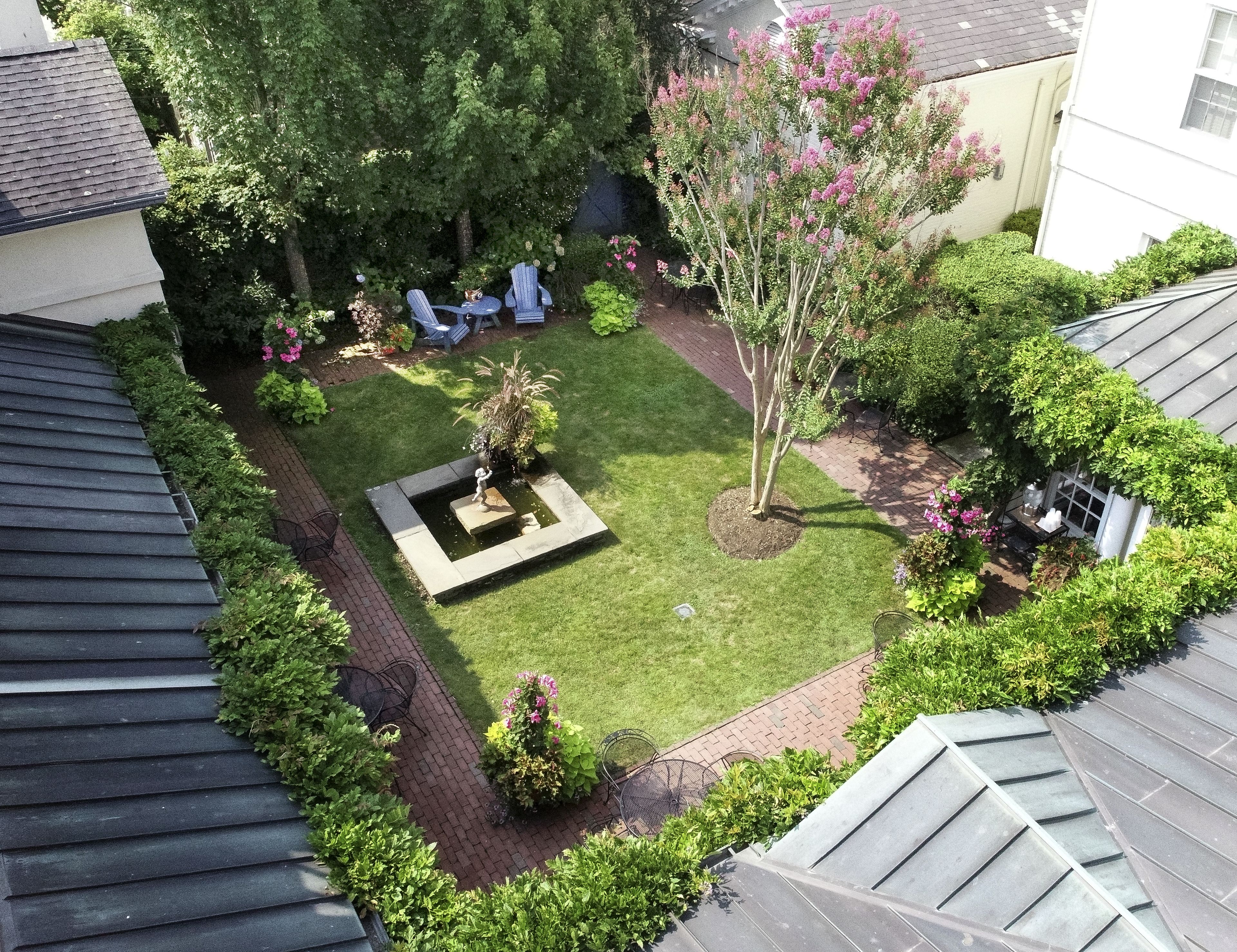 A rooftop garden with a small pond, seating area, and various plants.