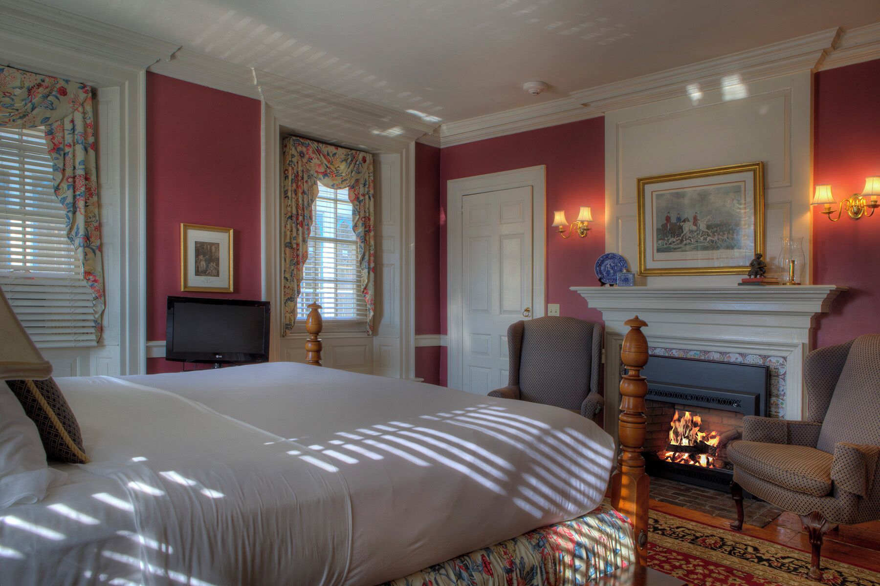 A hotel room with a large bed, a fireplace, a television, and a seating area with chairs.