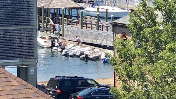 A marina with boats docked, a covered area with people, and a building with a sloped roof. - Francis Malbone House Inn (Newport)