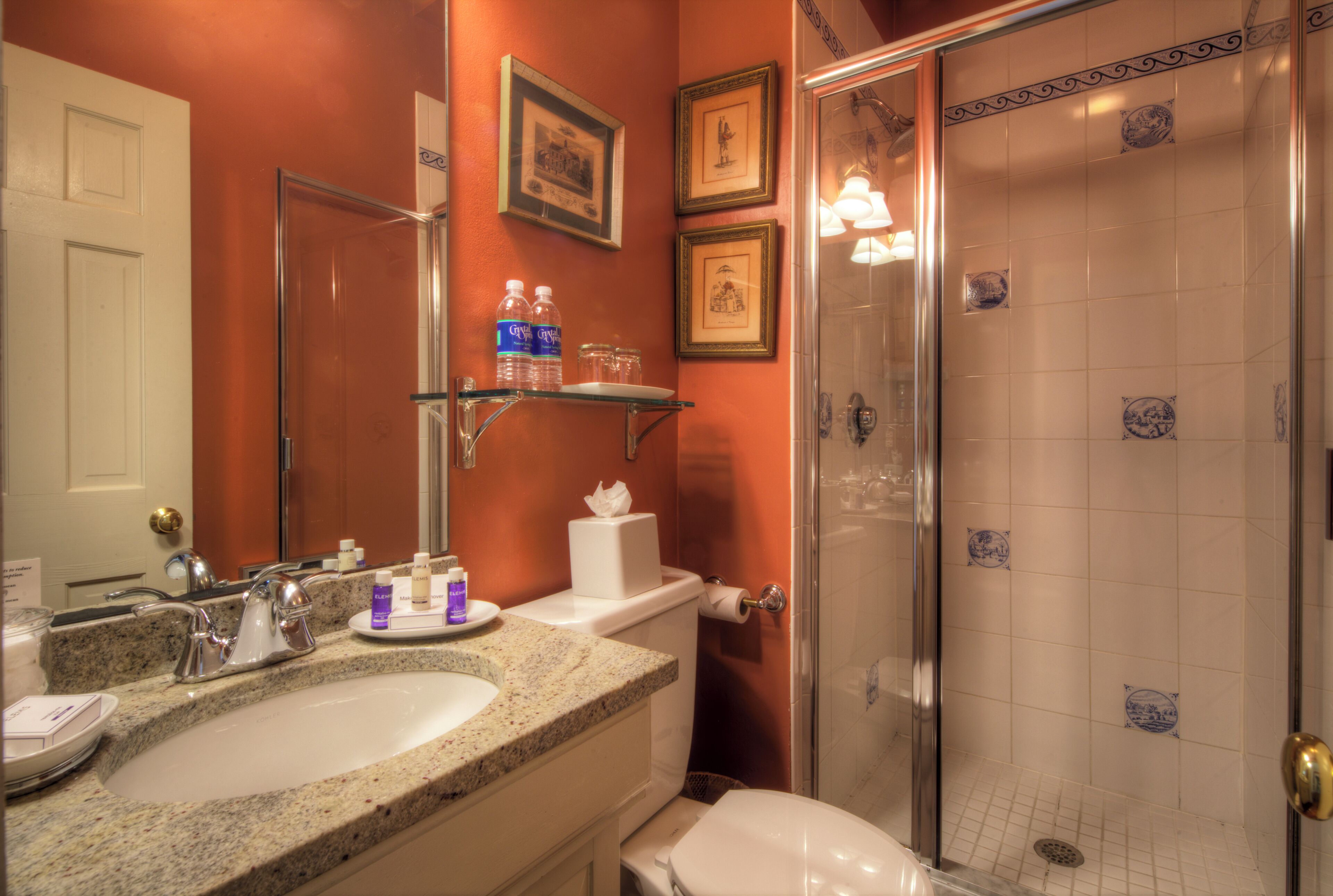 A bathroom with a granite countertop sink, a toilet, and a glass-enclosed shower.