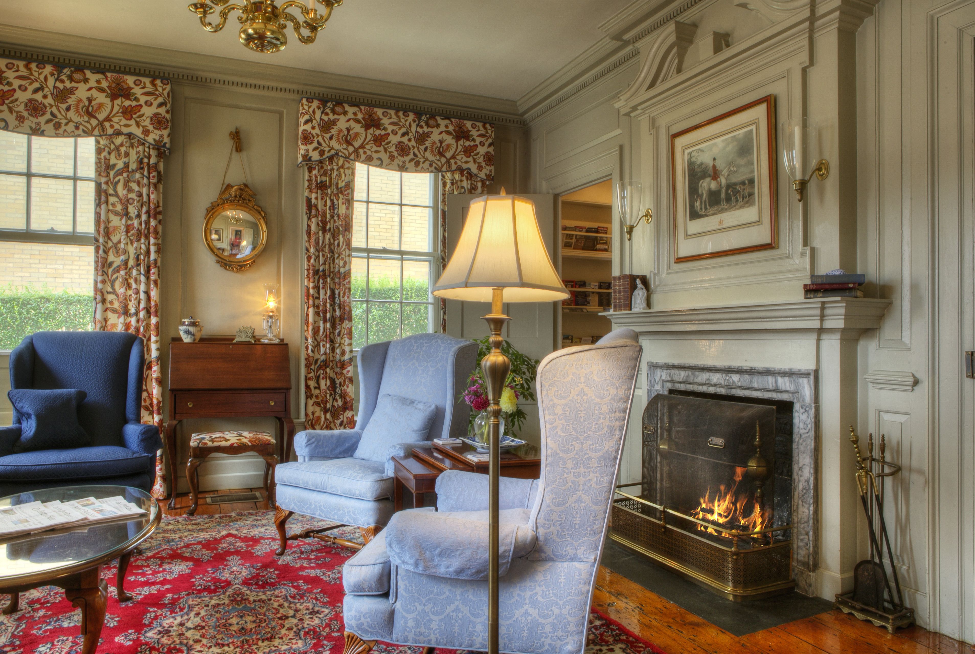 A traditional living room with a fireplace, two armchairs, a coffee table, and a lamp.