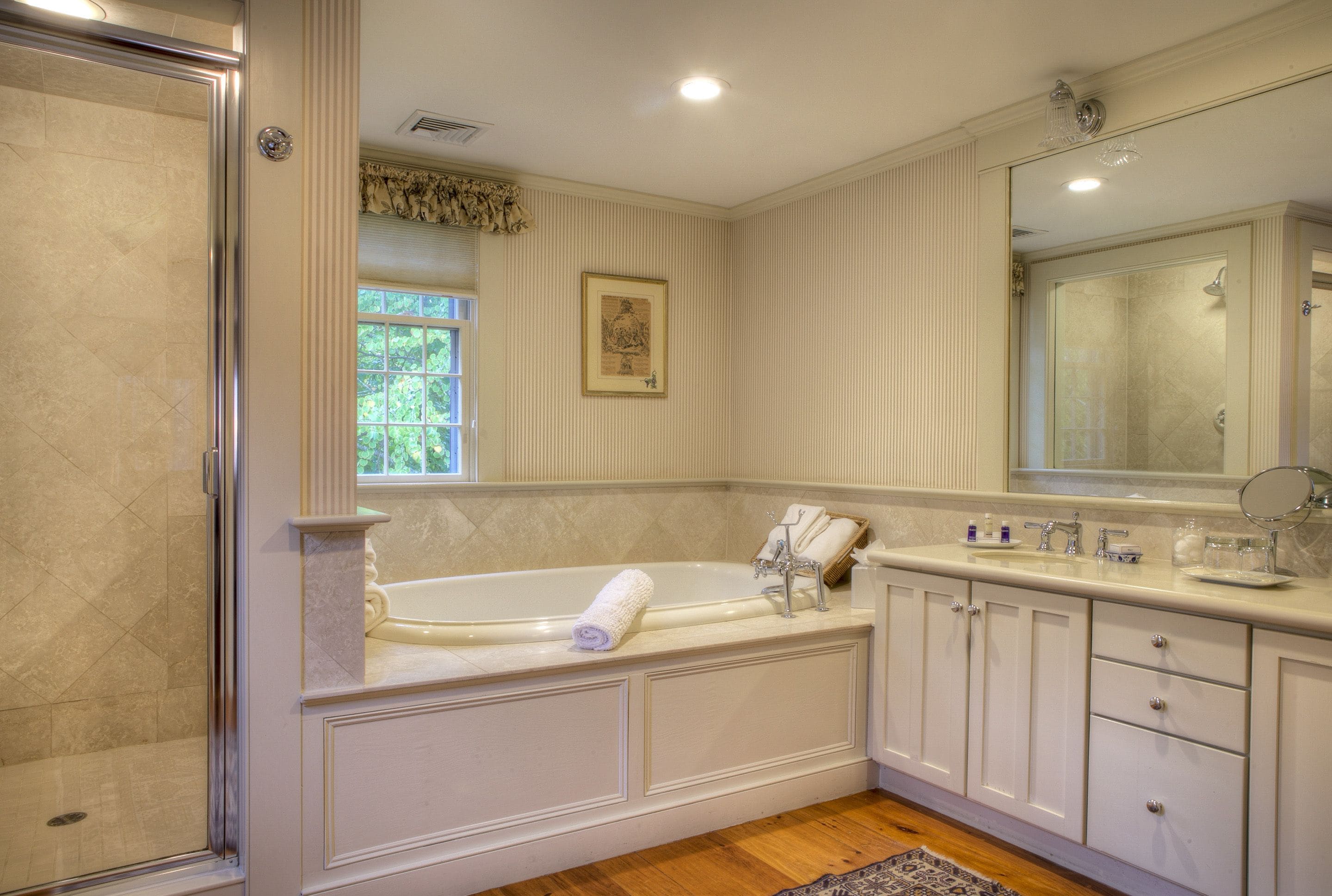 A spacious bathroom with a large bathtub, a walk-in shower, and a vanity with a mirror.