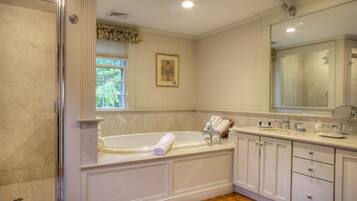 A spacious bathroom with a large bathtub, a walk-in shower, and a vanity with a mirror.