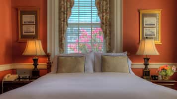 Una habitación de hotel con una cama grande, dos lámparas de noche, un teléfono y una ventana con cortinas florales.